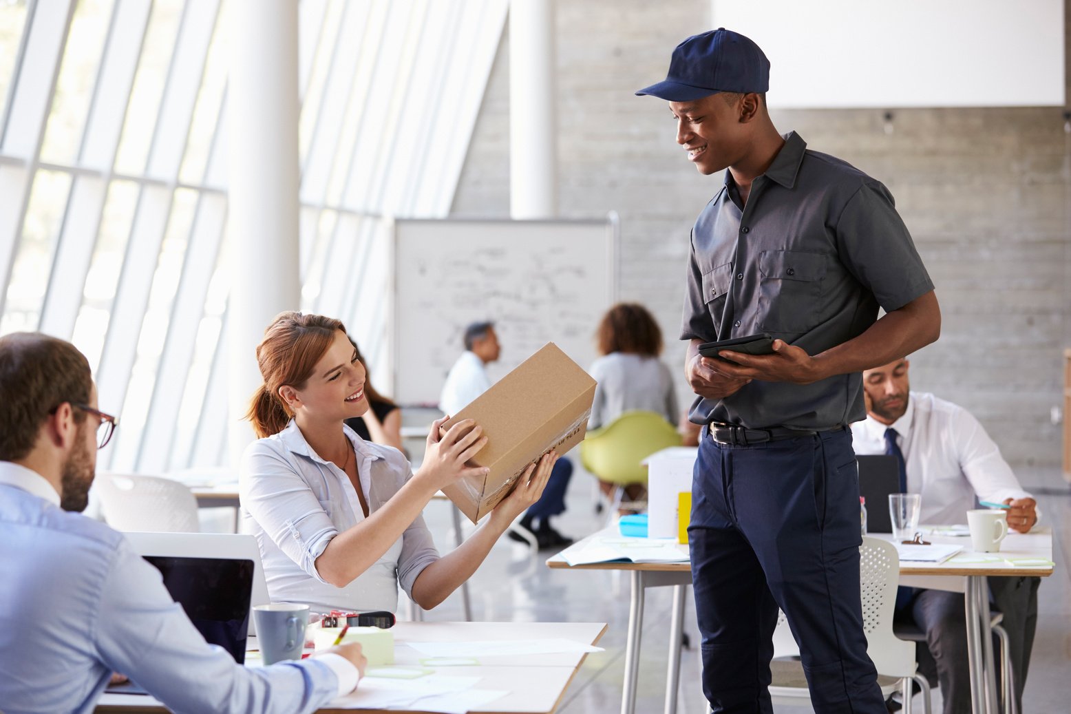 Courier Delivering Package to Businesswoman in Busy Office